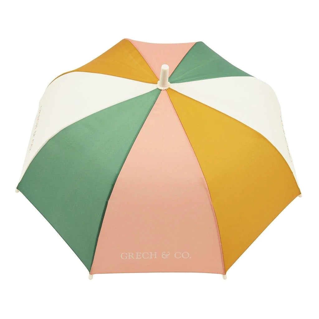 A view of the same umbrella from the top looking down on a white background. The umbrella has colourful fabric panels in off-white, mustard yellow, pink and green with the Grech & Co logo written along the bottom edge of some of the panels in contrasting colour ways.