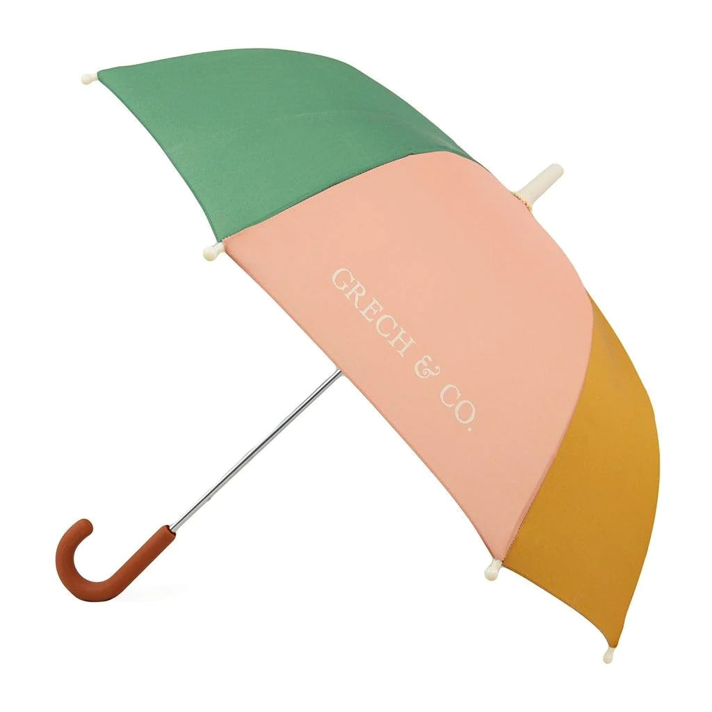 Grech & Co kids umbrella opened fully on a white background. The umbrella has colourful fabric panels in green, pale pink and mustard yellow.  The handle is curved and light brown.