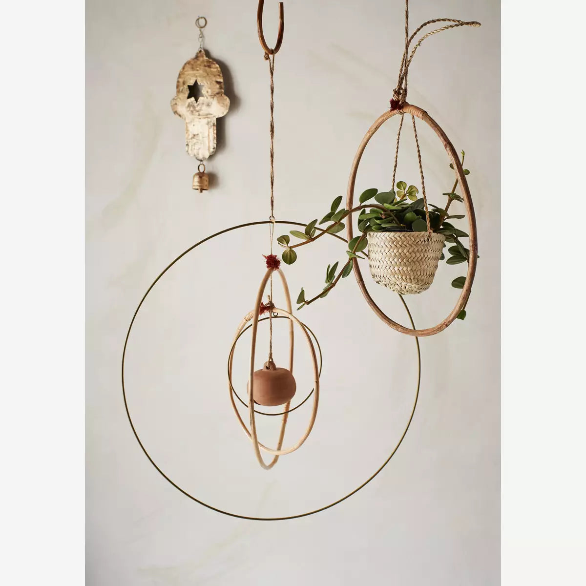 Interiors image of the straw hanging basket hung inside a bamboo ring and alongside a brass ring and other decorative home accessories.